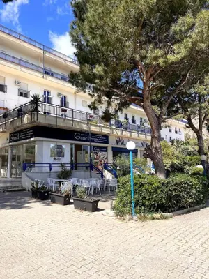 a building with tables and chairs in front of it at Nuovo appartamento sul mare immerso nel verde in Palermo