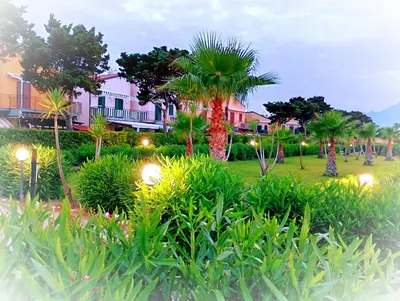 a park with palm trees and houses with lights at Villaggio 101 Pini in Buonfornello