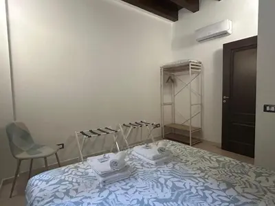 a bedroom with a bed and a chair and a closet at Casa Didi - Cattedrale in Palermo