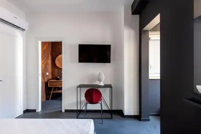 a bedroom with a red chair and a table at Massimo Foyer 53 by Wonderful Italy in Palermo