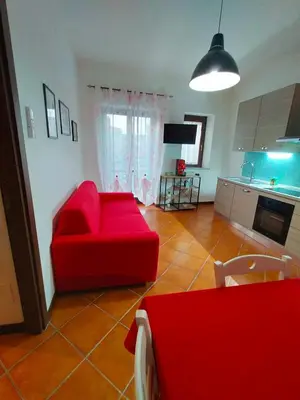 a living room with a red couch and a kitchen at Casa Marite' in Palermo