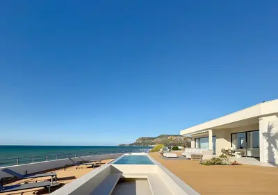 a building with a swimming pool next to the ocean at Solemar Sicilia - Villa Gloria in Ficarazzi