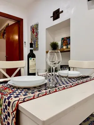 a table with a bottle of wine and glasses on it at Scala Dei Normanni in Palermo