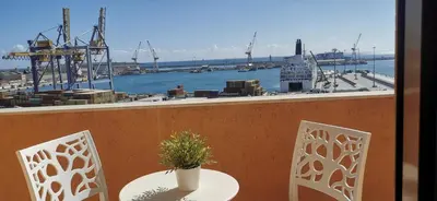 a table and chairs on a balcony with a view of a harbor at port side Palermo in Palermo
