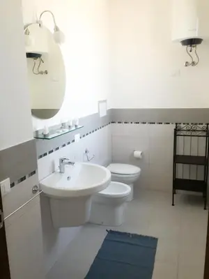a white bathroom with a sink and a toilet at Casa Oltremare UnmarediBlu in San Vito lo Capo