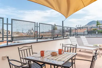 a table and chairs on the roof of a building at Candelai Apartments by Wonderful Italy in Palermo
