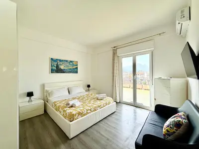 a white bedroom with a bed and a large window at La Coccola in Palermo