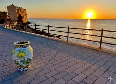 a vase sitting on a sidewalk next to the ocean at Vicolo a Mare in Porticello