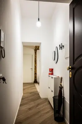 a hallway with white walls and wooden floors and a door at Casa Mazzarino - Exclusive Vucciria Apartment in Palermo