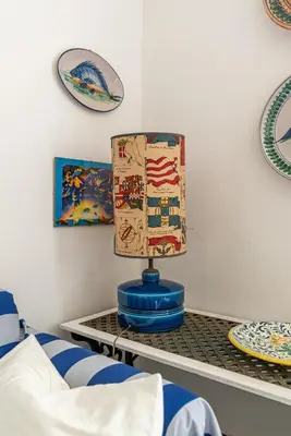 a lamp on a table with plates on the wall at Isola delle Femmine Apartments by Wonderful Italy in Isola delle Femmine