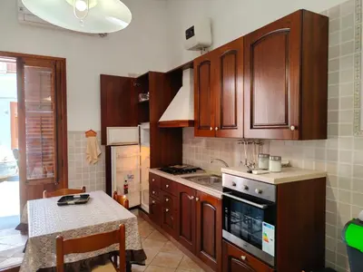 a kitchen with wooden cabinets and a table and a stove at Le Case di Sole San Vito Lo Capo in San Vito lo Capo