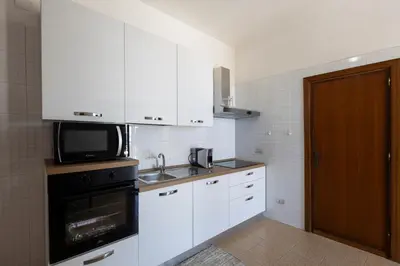 a kitchen with white cabinets and a sink and a microwave at I Piani Apartment in Trabia