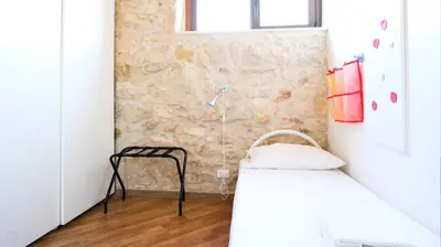 a bedroom with two beds and a stone wall at Visitsicilia Villa Cialoma in Scopello