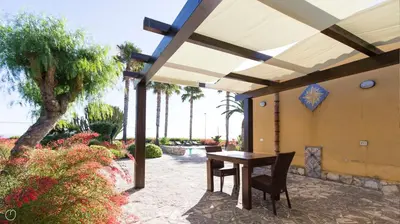 a patio with a table and chairs under a pavilion at Visitsicilia Villa Cialoma in Scopello
