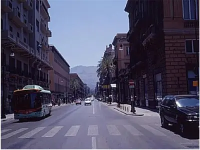a city street with cars and a bus on the road at Casa Colorata in Palermo