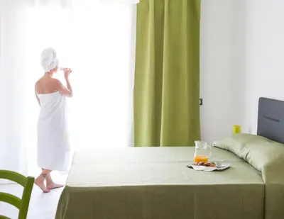 a woman in a white dress standing by a window at Stanze del Mare in Balestrate