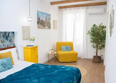a bedroom with a bed and a yellow chair at Home Simo al Capo in the old center of Palermo in Palermo