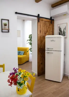 a kitchen with a refrigerator and a table with flowers at Home Simo al Capo in the old center of Palermo in Palermo