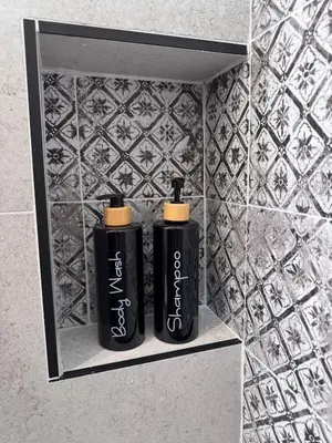 two black bottles sitting on a shelf in a bathroom at Home Simo al Capo in the old center of Palermo in Palermo