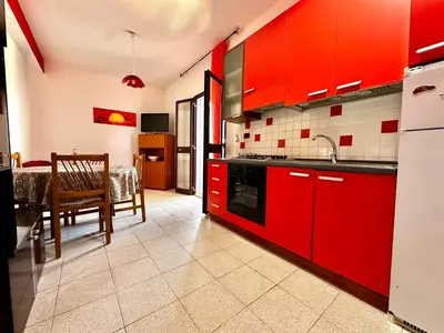 a kitchen with red cabinets and a dining table at Casa del Sole in Campofelice di Roccella