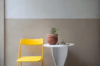 a yellow chair and a table with a plant on it at Cortile Galletti - Cool Flat with Private Courtyard in Palermo