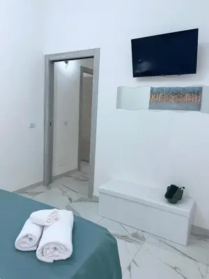 a white room with a tv and towels on a bed at Coco Memi Apartment in Palermo