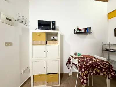 a room with a table and a cabinet with a microwave at Vicolo Giardi in Palermo