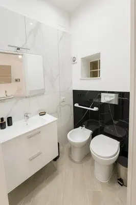 a white bathroom with a toilet and a sink at Trasi E Niesci Flat in Palermo