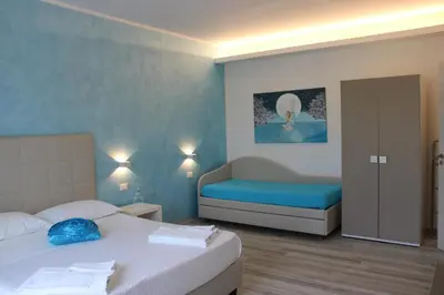 a hotel room with two beds and a couch at B&B Selene in San Vito lo Capo