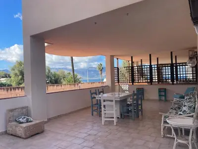 a room with a table and chairs and windows at Casa del Sorriso in Isola delle Femmine