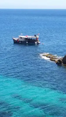 a boat in the water next to a rocky shore at Apartment in Villa a Mondello in Mondello