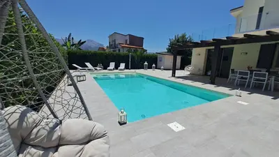 a swimming pool with chairs and a house at Villa Elios Adriana2 in Lascari