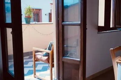 a person sitting in a chair looking out of a door at Epic terrace in Kalsa in Palermo