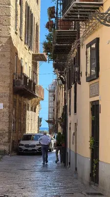a man walking down a street in a city at Epic terrace in Kalsa in Palermo