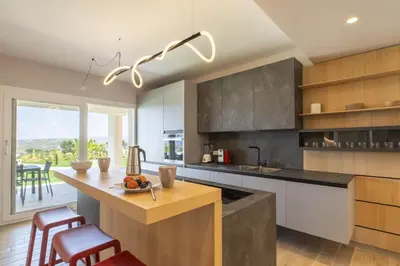 a kitchen with a counter and a table with chairs at Villa Aversa by PosarelliVillas in Castellammare del Golfo
