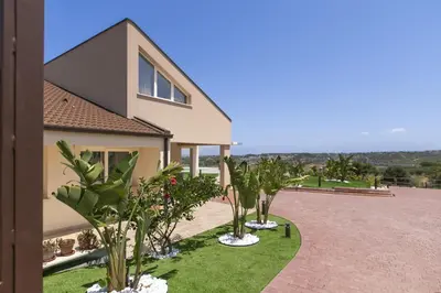 a house with palm trees in front of a driveway at Villa Aversa by PosarelliVillas in Castellammare del Golfo