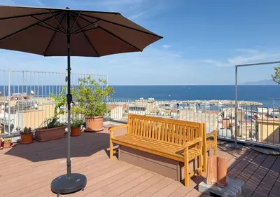 a wooden bench sitting on a deck with an umbrella at Solemar Sicilia - Casa Sabine in Santa Flavia