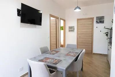 a dining room with a table with chairs and a flat screen tv at Adagos in Palermo