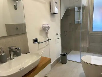 a bathroom with a white sink and a shower at Vulpi 29 Apartment-Deluxe in Palermo