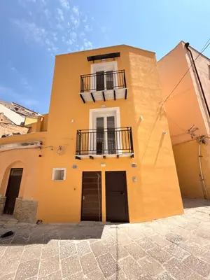 a yellow building with a window and a balcony at Dimora Santa Spina in Palermo
