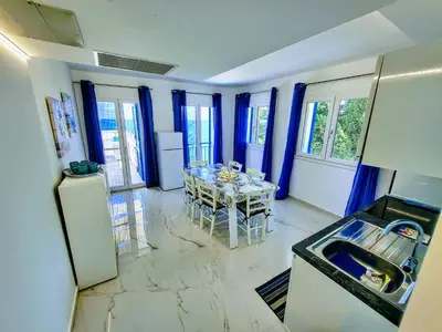 a kitchen with a table and a kitchen with blue curtains at Sunset in Santa Flavia