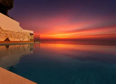 a swimming pool with a sunset in the background at Sunset in Santa Flavia