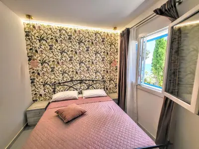 a small bedroom with a pink bed with a window at Sunset in Santa Flavia