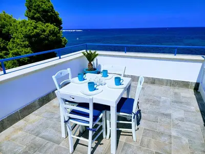 a white table and chairs on a balcony with the ocean at Pearl in Santa Flavia