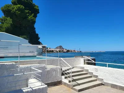 a staircase leading to a swimming pool next to the water at White Coral in Santa Flavia