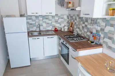 a kitchen with white cabinets and a stove top oven at Casetta Giardinetto in Altavilla Milicia