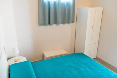 a small bedroom with a blue bed and a cabinet at Casetta Giardinetto in Altavilla Milicia