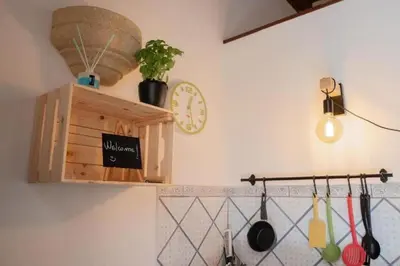 a kitchen with a clock and a shelf with utensils at Casa Duci - Historic center in Palermo