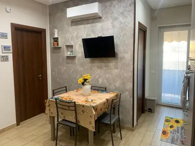 a dining room table with chairs and a television on a wall at Girasole Marino in Palermo