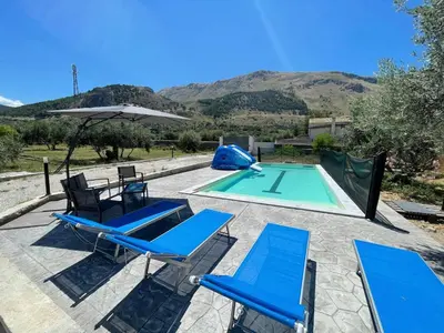 a group of blue chairs and a swimming pool at Villa Verde - Nature Holiday Home in Carini